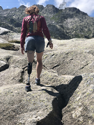 Female hikes up rocks with leg prosthetic