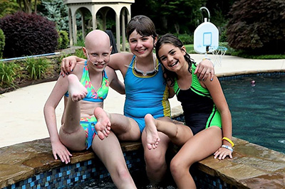 Three females with rotationplasty sit by pool