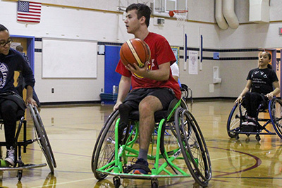 Male with leg amputation plays basketball in sports wheelchair