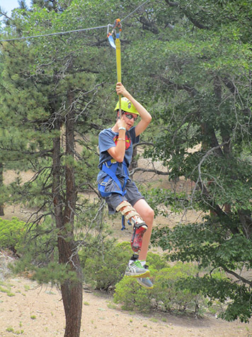 Individual with leg prosthetic ziplining through the trees